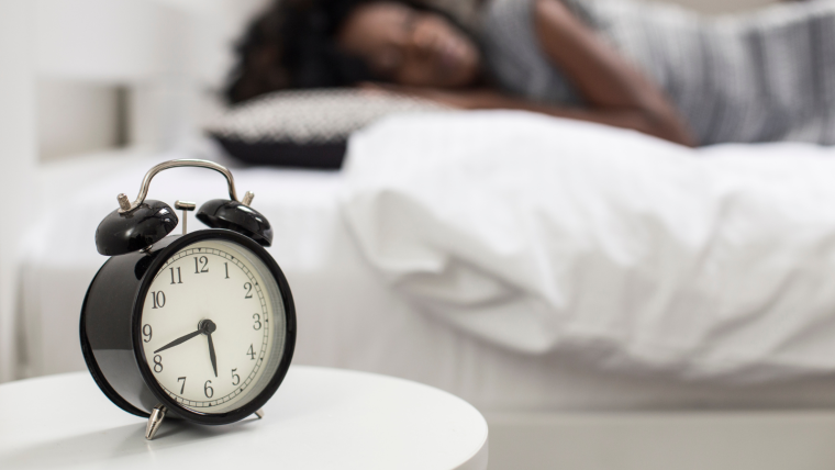 Person sleeping with alarm clock