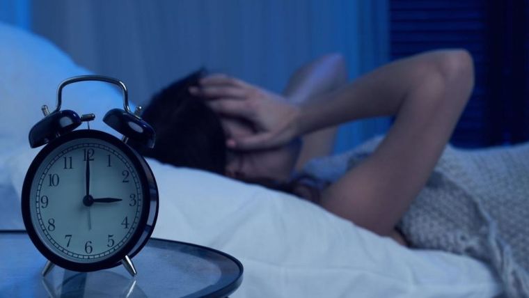 person unable to sleep with an alarm on the foreground