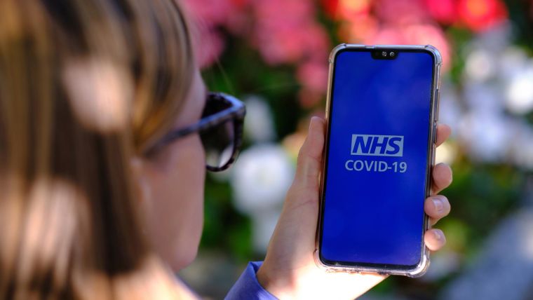 A person holds a mobile phone displaying the NHS COVID-19 app