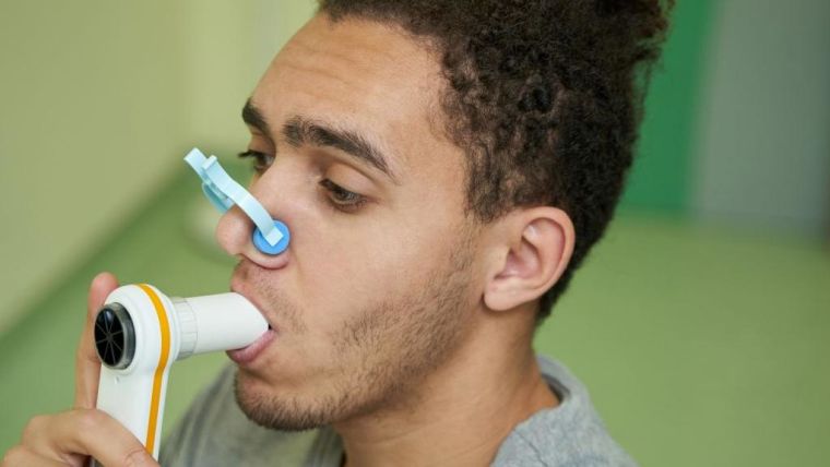 Young man with using the inhaler with a peg in his nose