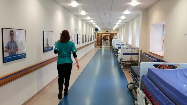 Female NHS worker walking in hospital corridor during the day