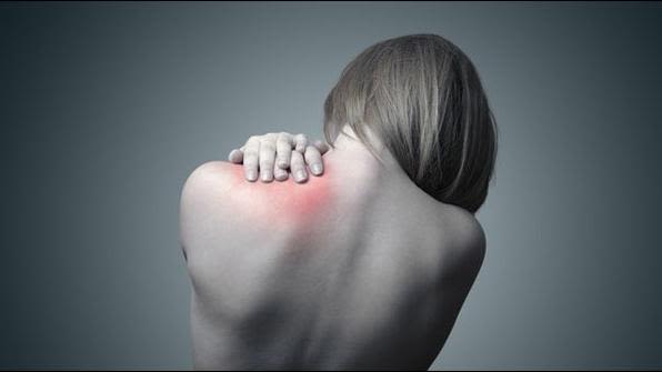 View of a woman's back that she is clutching in pain