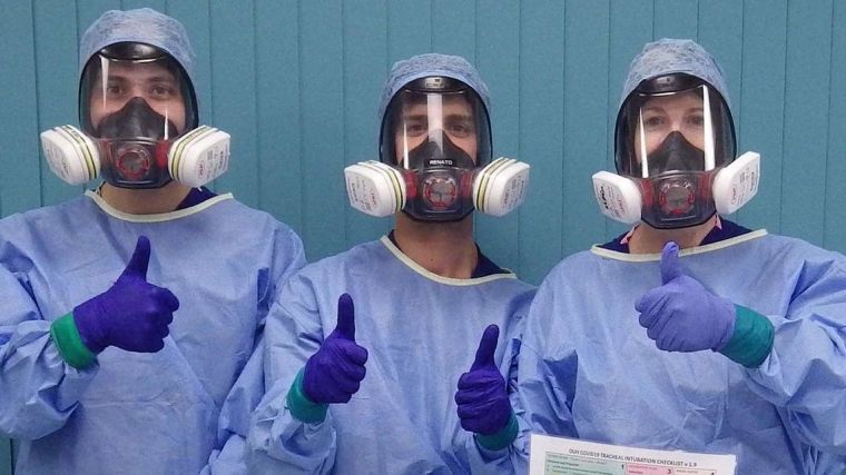 Three medical staff members with blue medical gowns and filtering facepiece