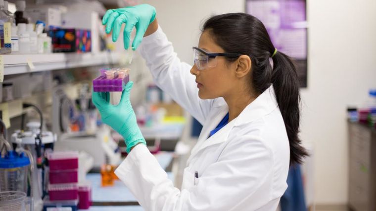 Female scientist in labcoat wearing nitrile gloves, doing experiments in lab,