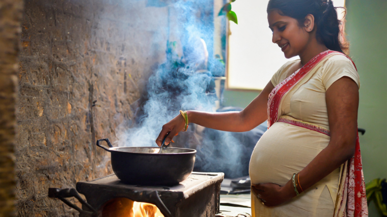 Pregnant woman of Indian ethnic background cooking in her kitchen