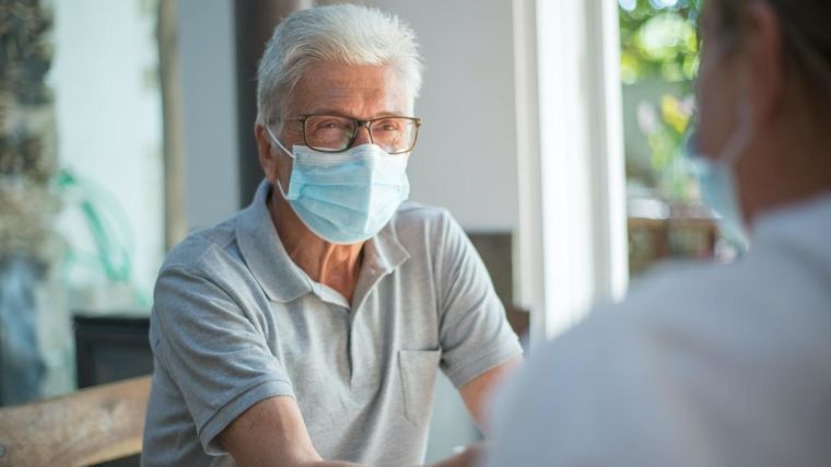 Man wearing a face mask meeting with a healthcare professional