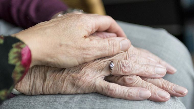 A young person's hand on an older person's hand